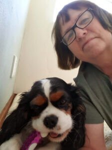 A woman is laying on the floor with a dog.